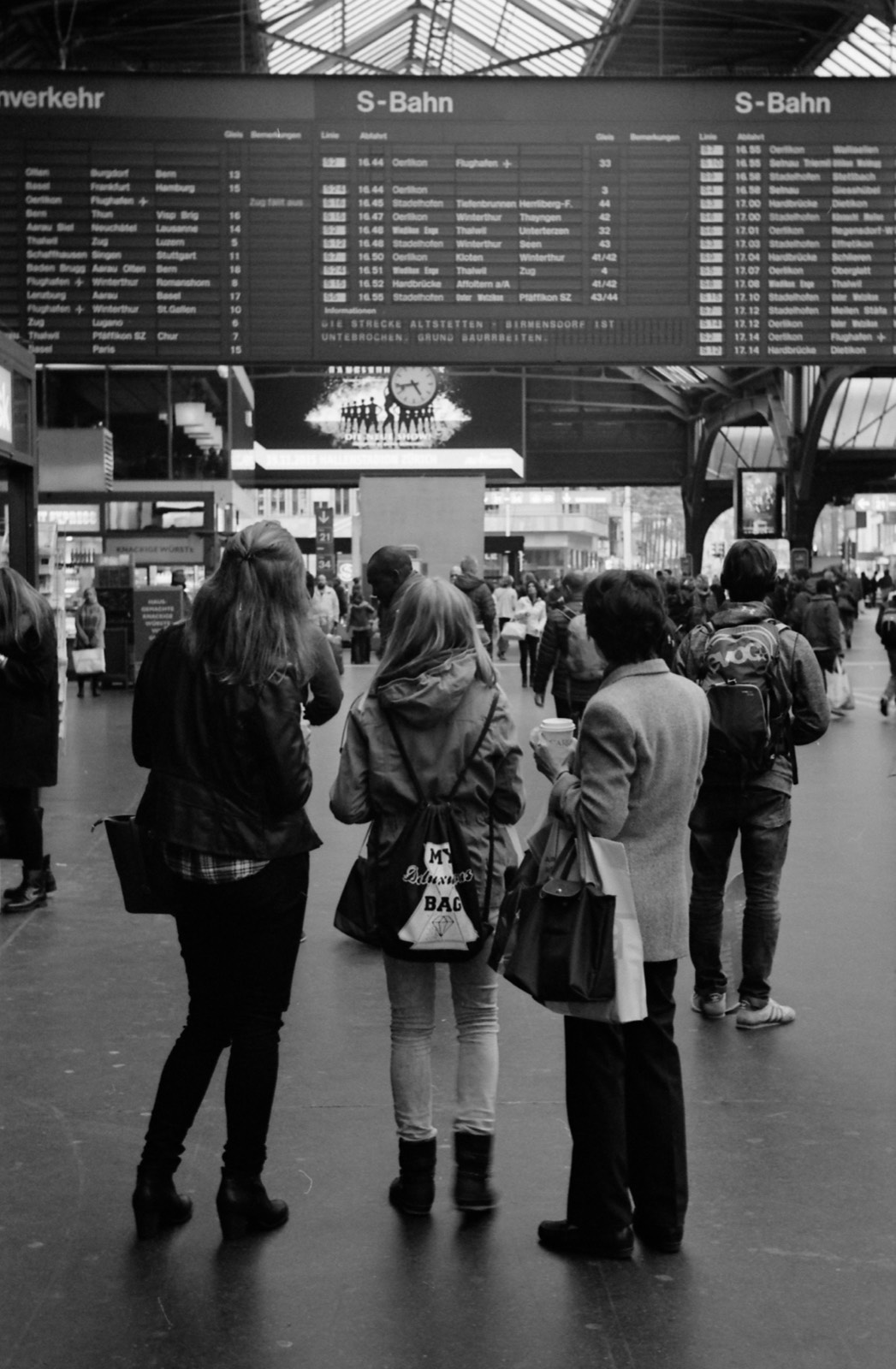 Travellers looking up at the departures board in Zurich main station